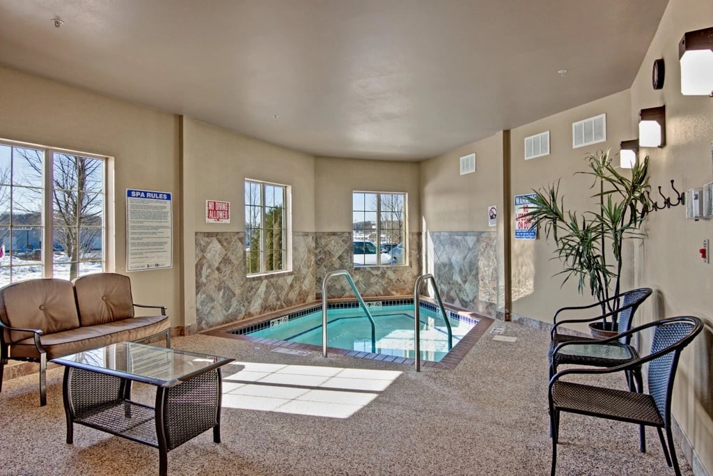 Indoor swimming pool with seating area and spa rules sign.