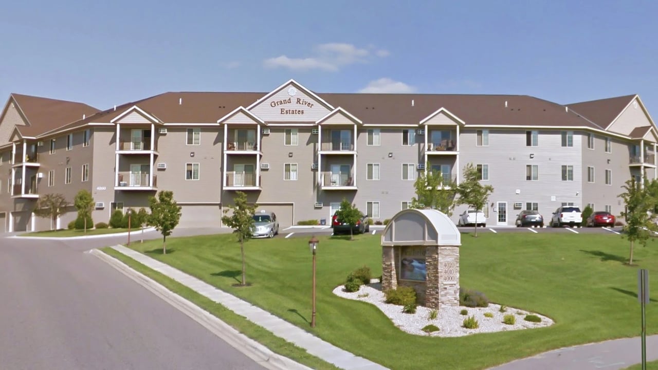 Grand River Estates apartment building exterior with balconies and parking lot.
