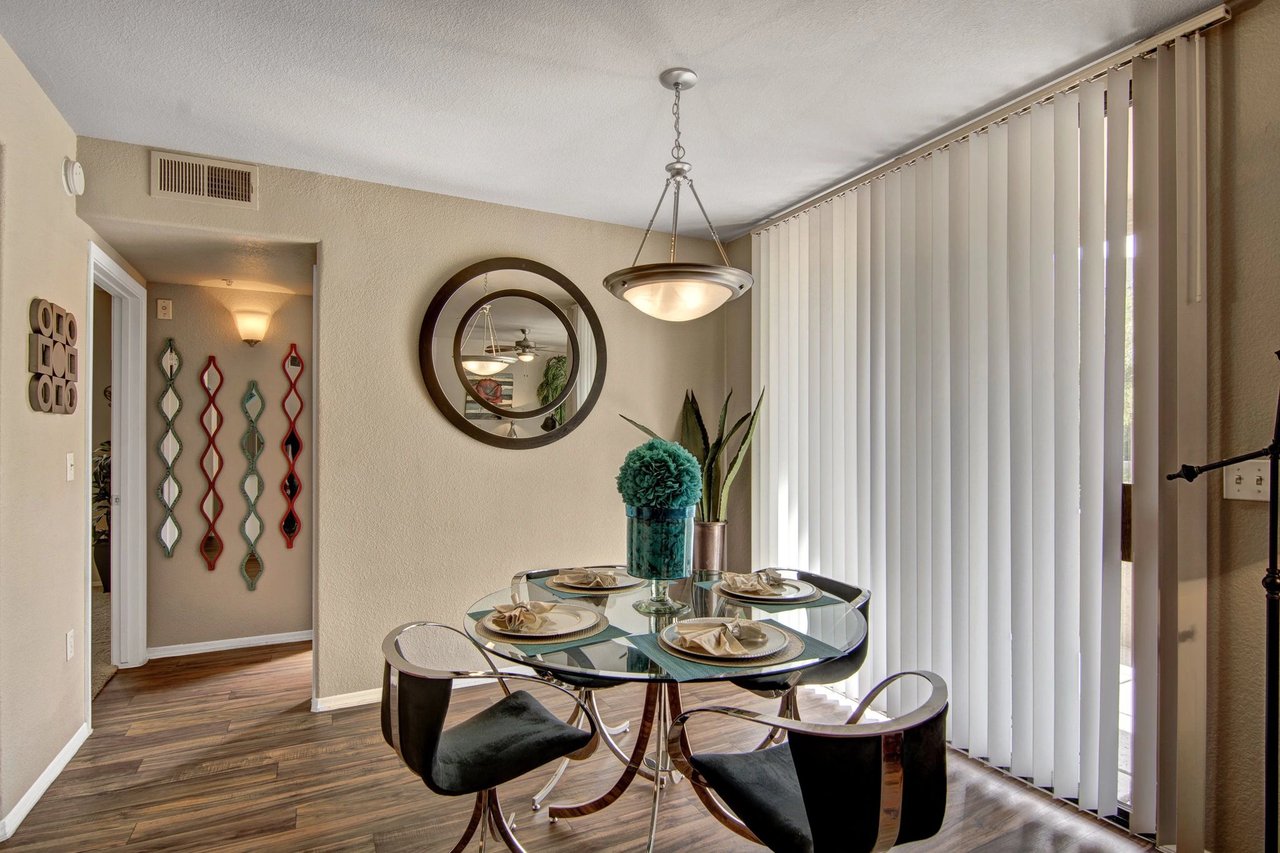 Dining area with glass table and chairs, decorative mirrors on wall.