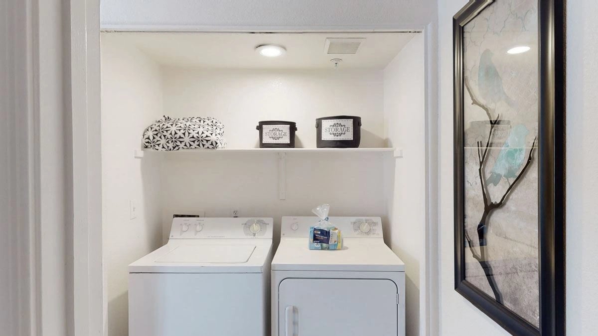 In-unit washer and dryer with storage shelves above.