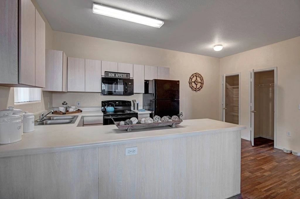 Kitchen with white cabinets, black appliances, and a breakfast bar.