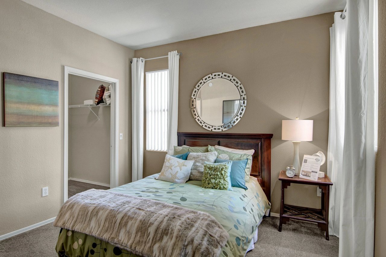 Cozy bedroom with a queen-size bed, decorative pillows, a large mirror, and a closet.