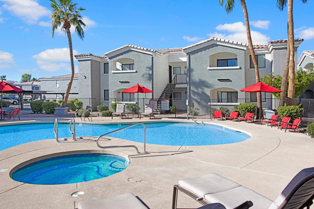 Resort-style pool and hot tub with lounge chairs and palm trees.