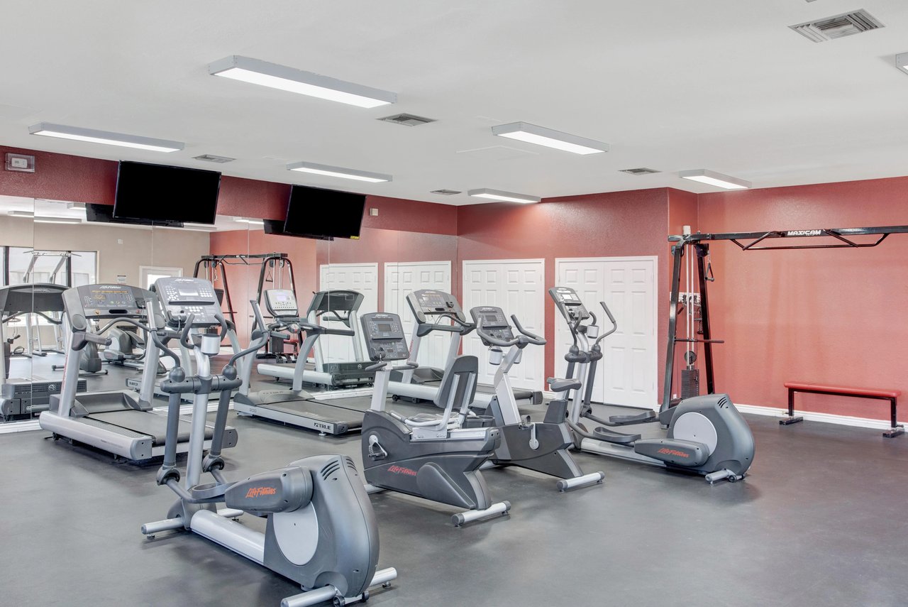 Gym with treadmills, ellipticals, stationary bikes, and weight machines.