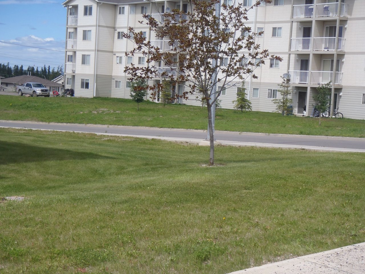 Exterior view of a multi-story apartment building with a truck parked in front.