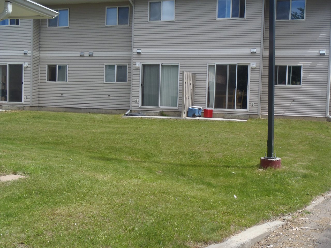 Exterior view of apartment building with grassy yard and pavement.