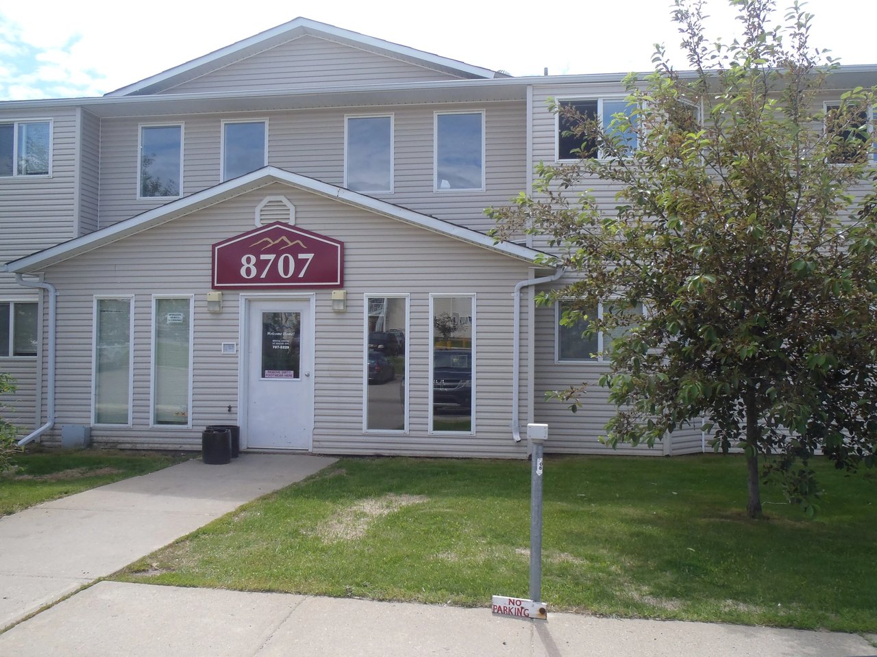 Building exterior with address 8707 and a small tree.