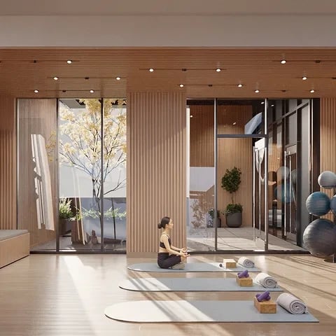 A woman meditates in a serene yoga studio with natural light and plants.