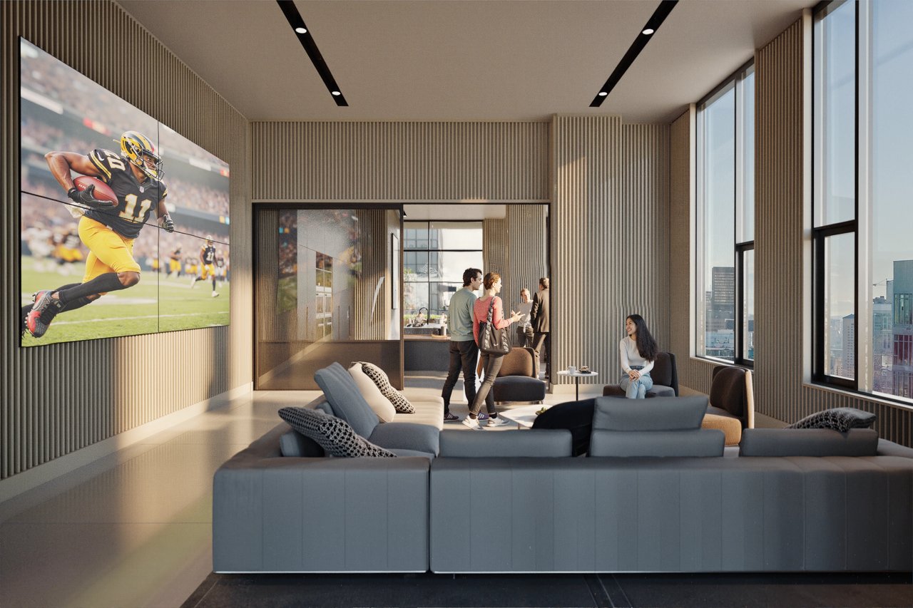 A communal lounge area with a large screen displaying a football game and people socializing.