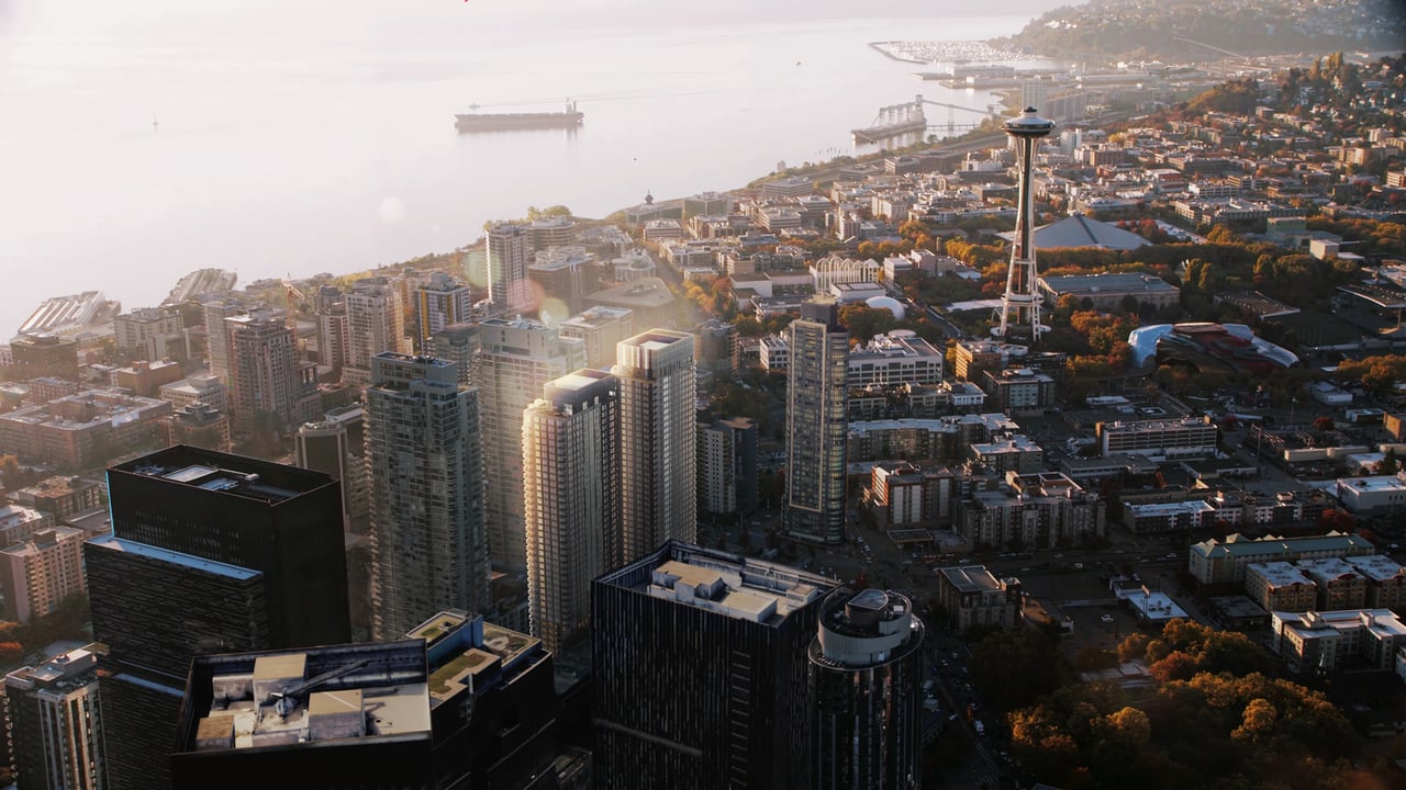 Aerial view of a dense urban skyline with skyscrapers and water in the background.