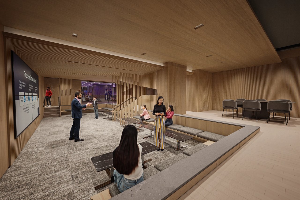 People in a modern community lounge with a presentation screen and seating areas.