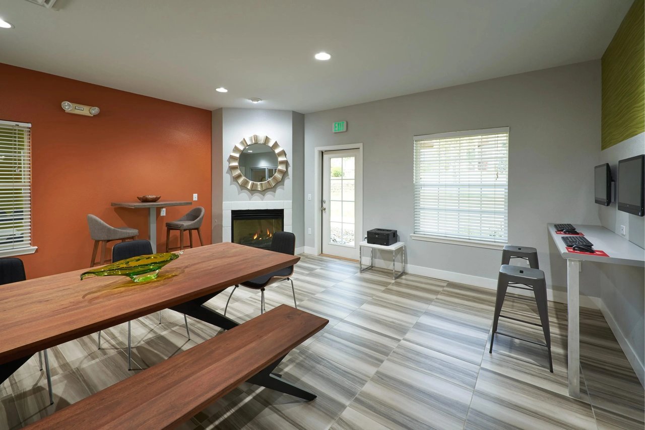 Community room with a fireplace, large dining table, and computer workstations.