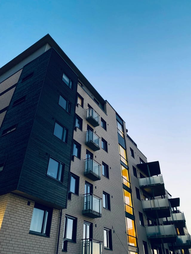 Exterior of a modern apartment building with balconies against a clear blue sky.