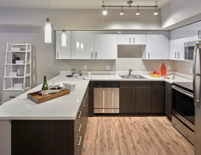 Modern kitchen with white countertops, dark wood cabinets, stainless steel appliances, and pendant lighting.
