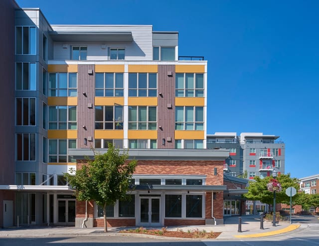 Modern apartment building exterior with colorful accents and large windows.