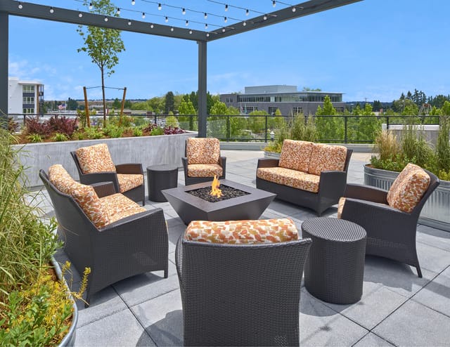 Outdoor patio seating area with fire pit and string lights.