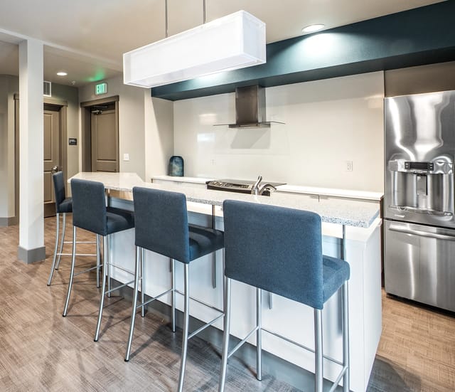 Modern kitchen island with blue bar stools and stainless steel appliances.