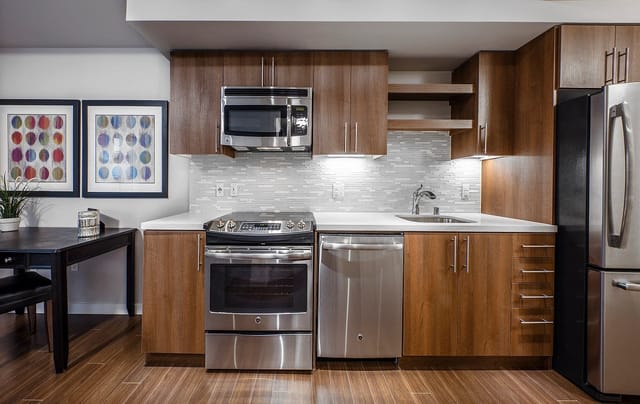 Modern kitchen with stainless steel appliances, wood cabinets, and a dining area.