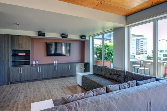 Community lounge area with large sectional sofa, television, and built-in cabinets.