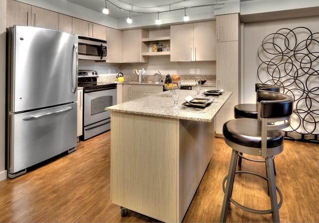 Modern kitchen with stainless steel appliances and an island with bar stools.