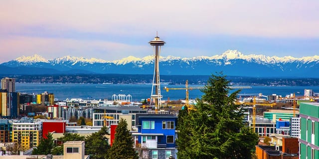 View of Seattle skyline with Space Needle and snow-capped mountains in background.