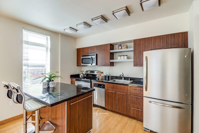Modern kitchen with stainless steel appliances, granite countertops, and island seating.