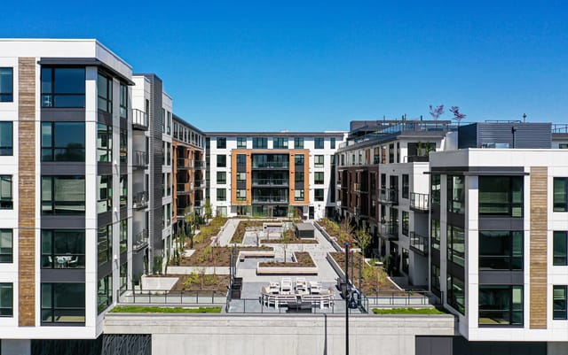 Exterior courtyard and buildings of a modern multifamily apartment complex.