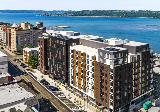Modern apartment buildings with a view of the water and mountains.
