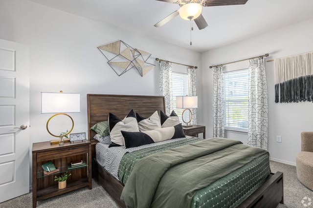 A stylish bedroom with a king-sized bed, modern decor, and a ceiling fan.