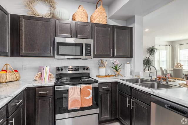 Modern kitchen with dark wood cabinets, stainless steel appliances, and marble countertops.