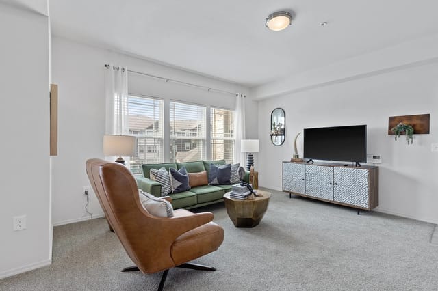 Stylish living room featuring a green sofa, armchair, coffee table, and a TV stand with a TV.