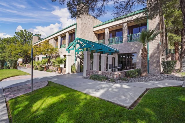 Exterior view of a two-story apartment building with teal entrance canopy and landscaped walkway.