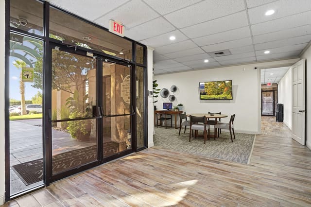 Leasing office lobby with glass entry doors, seating area, and a wall-mounted TV.