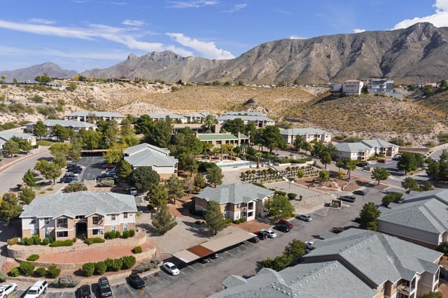 Aerial view of a desert apartment community with multiple buildings and a central pool.