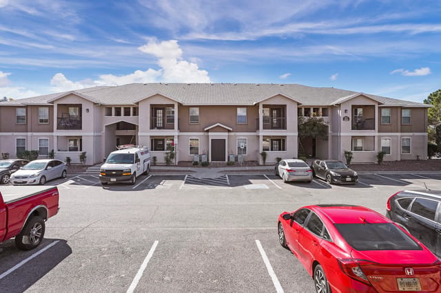 Exterior view of the apartment building with a parking lot in the foreground.
