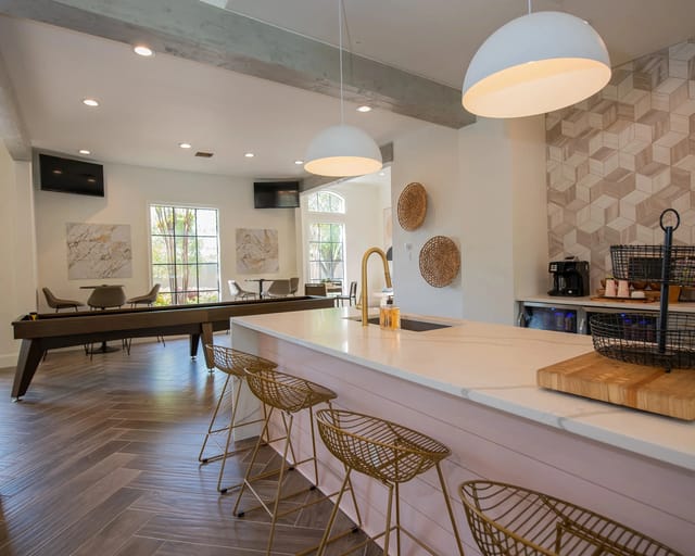 A kitchen with a white counter and a bar area with stools.