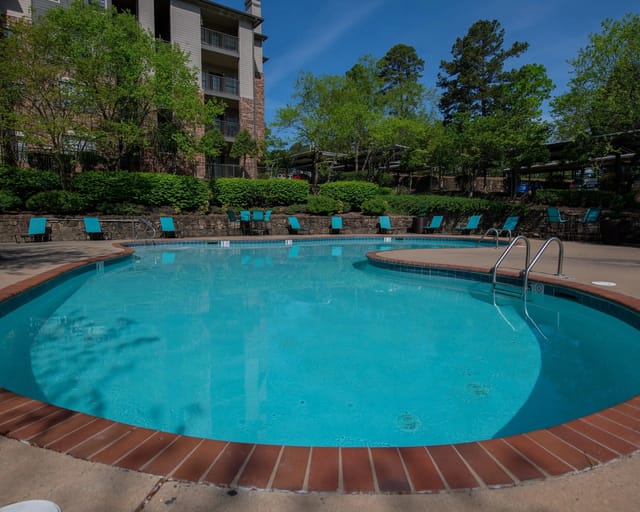 A round swimming pool with blue water and a brick border.