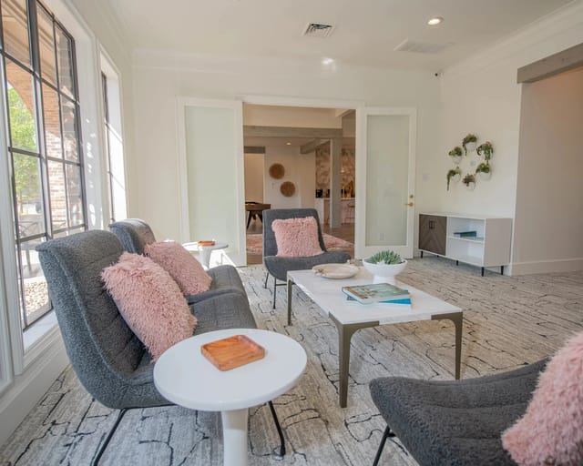 A living room with a grey couch, a white coffee table, and a pink cushion.