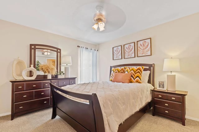 A bedroom with a bed, dresser, and mirror.