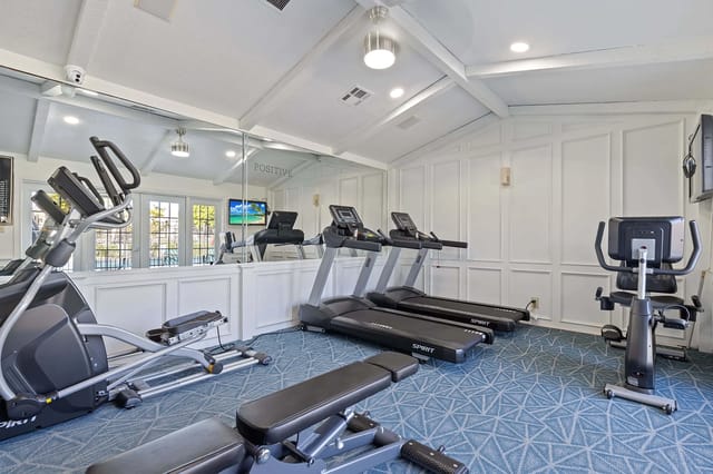 Gym with treadmills, elliptical, stationary bike, and weight bench