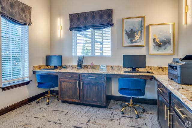 Shared community office area with two desks, monitors, and a printer.