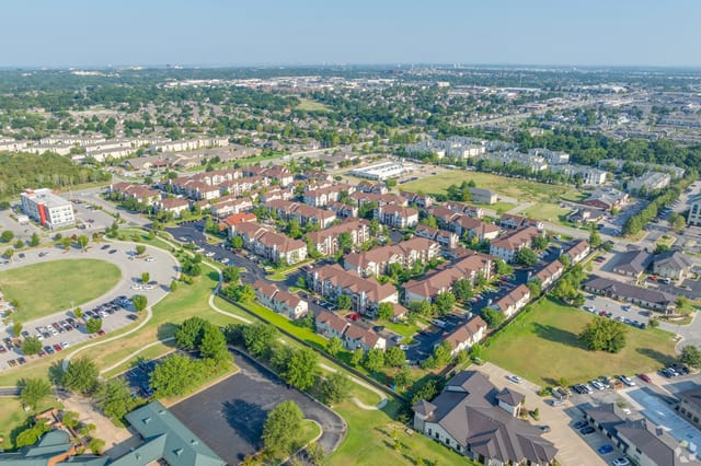 Aerial view of a large apartment community with multiple buildings, roads, and green spaces.
