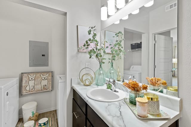 A bathroom with a white sink and a mirror.