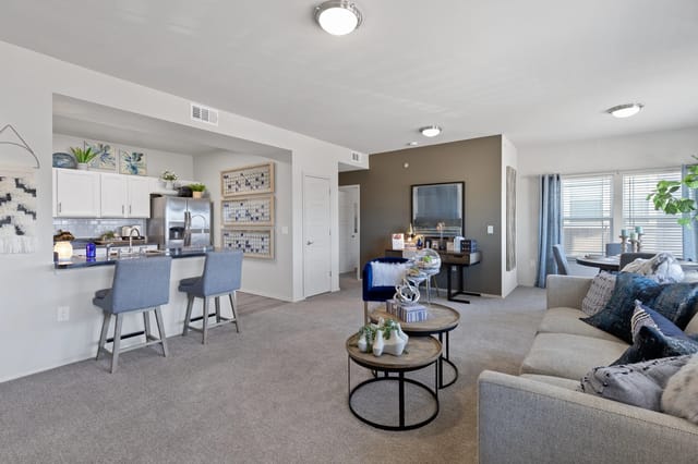 A living room with a grey couch and a round table in the middle.