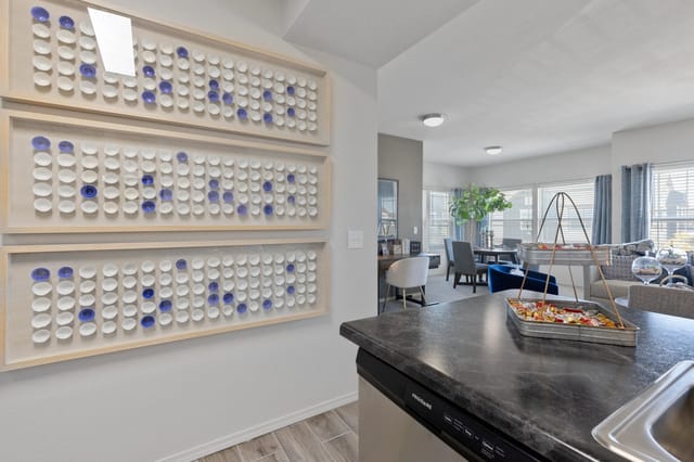 A kitchen with a black counter top and a wall with blue and white tiles.