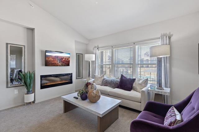 A modern living room with a purple chair and a fireplace.