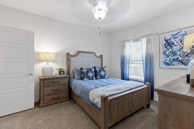 A bedroom with a bed, nightstand, and lamp.