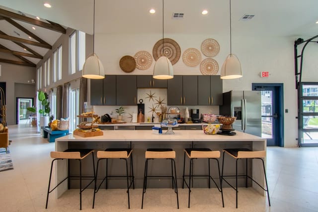 Modern community kitchen with a large island, pendant lights and gray cabinets.