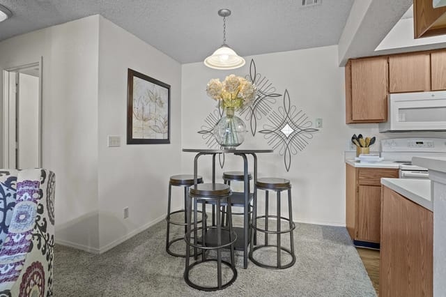 Dining nook with a tall, round table and four metal stools in a kitchen area.