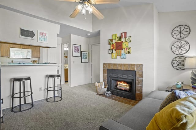 Living room with fireplace, sofa, and a kitchen pass-through with two bar stools.